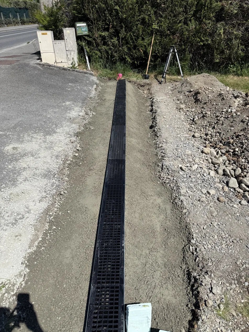 Pose d'un caniveau de drainage le long d'une voie, en Haute-Savoie
