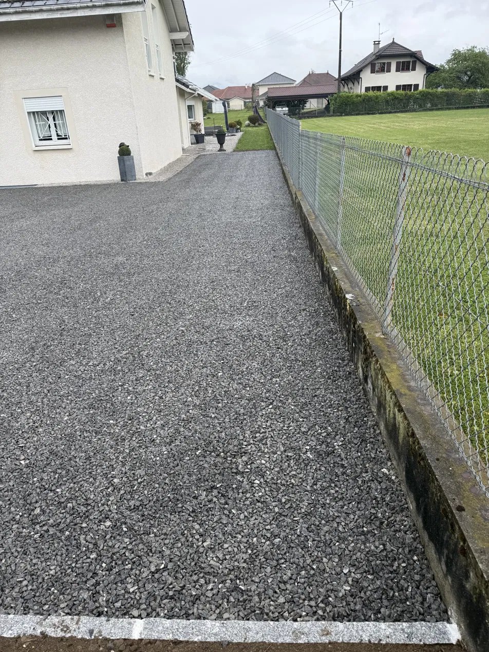 Allée en gravillon avec bordure, le long d'une maison